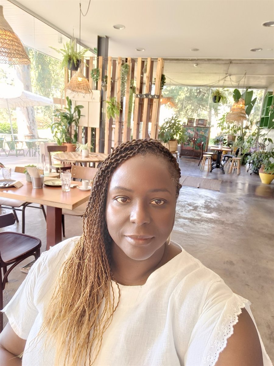 Samone Davis, founder of Soft Life Abroad, at a sunlit, plant-filled café in Almeirim, Portugal